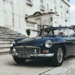 Dark blue vintage convertible parked in front of a stone building