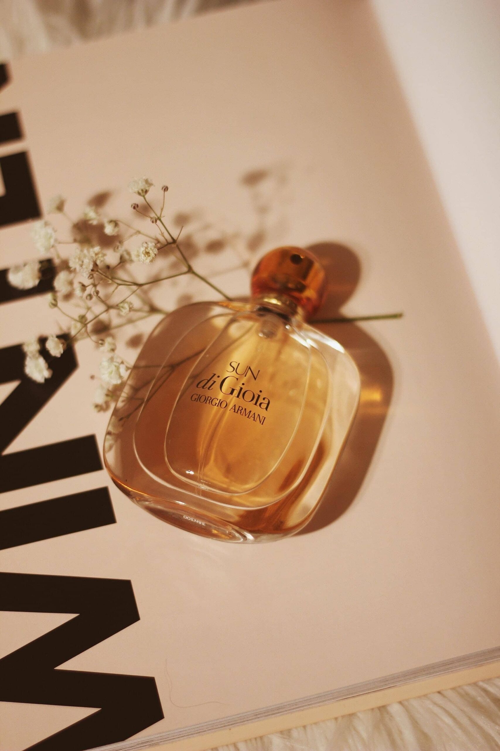 Perfume bottle and dried gypsophila resting on an open magazine