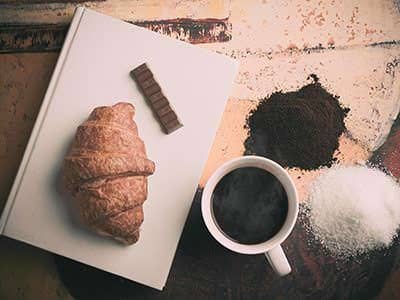 Croissant and chocolate beside a cup of black coffee