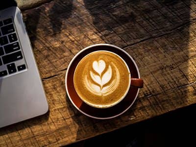 Latte with rosetta art next to a laptop