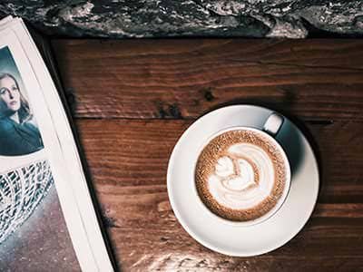 Cappuccino and a magazine on a wooden table