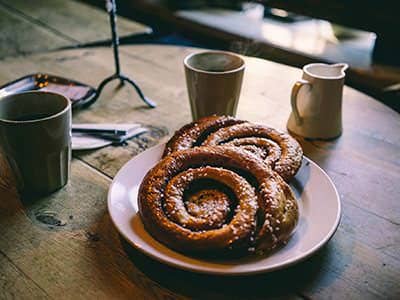 Cinnamon buns on a plate with coffee cups