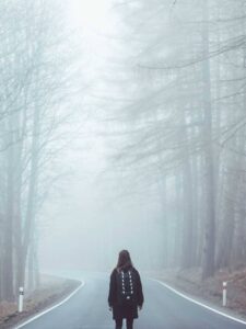 Walker with a backpack on a foggy forest road