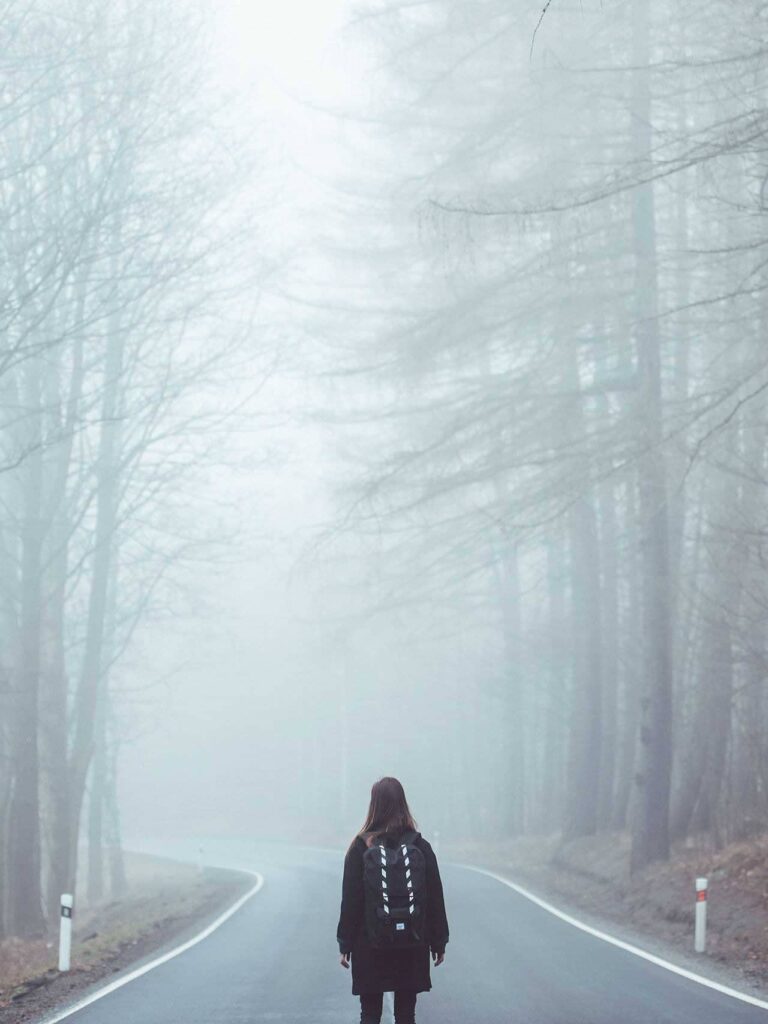 Walker with a backpack on a foggy forest road
