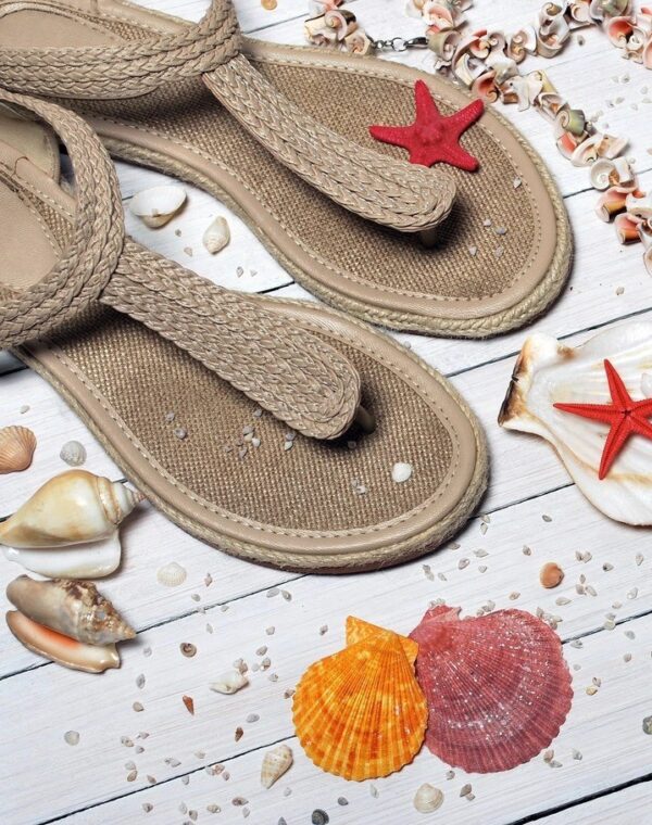 Sandals with shells on a wooden deck