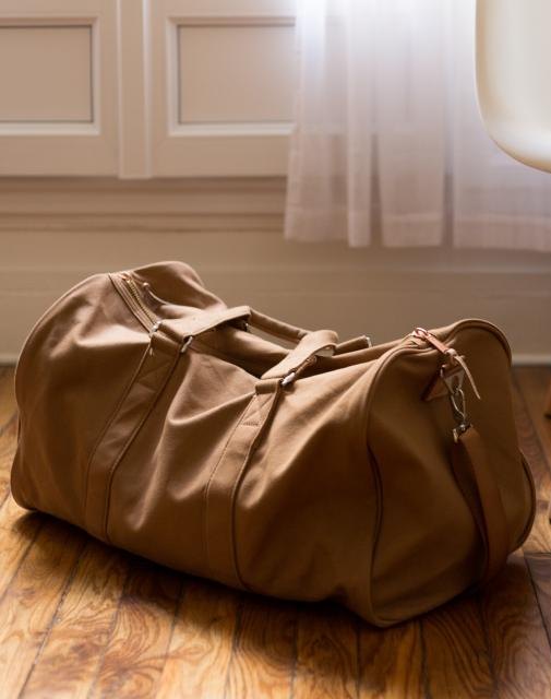Brown leather duffel bag on a wooden floor