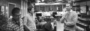 Three colleagues talking beside desks in an open studio office