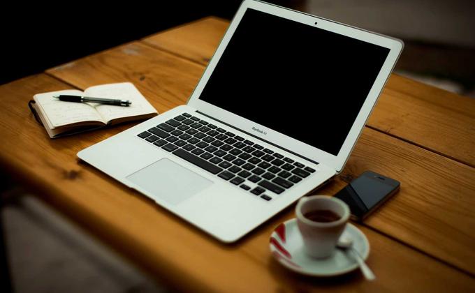 A laptop, notebook and coffee on a desk