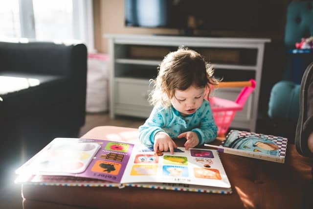 A toddler turning the pages of a picture book