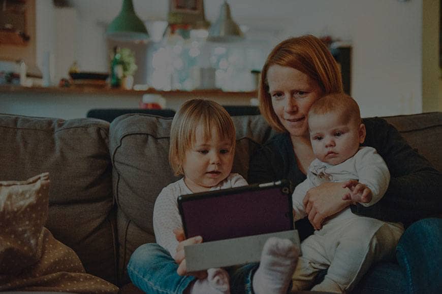 A parent reading with her two children at home