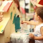 Children painting a wooden playhouse together