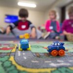 Children playing with toy cars on a play mat