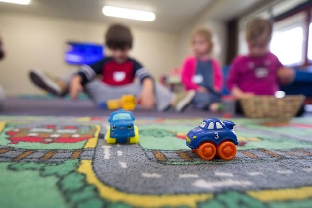 Children playing with toy cars on a play mat