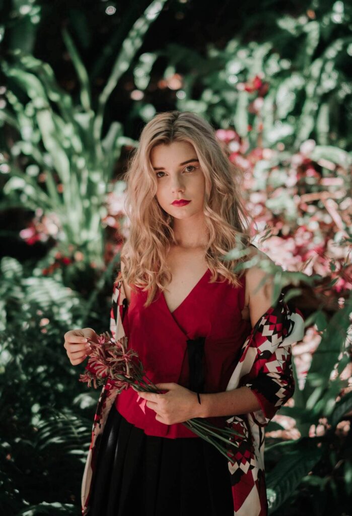 Model in a crimson dress among green foliage