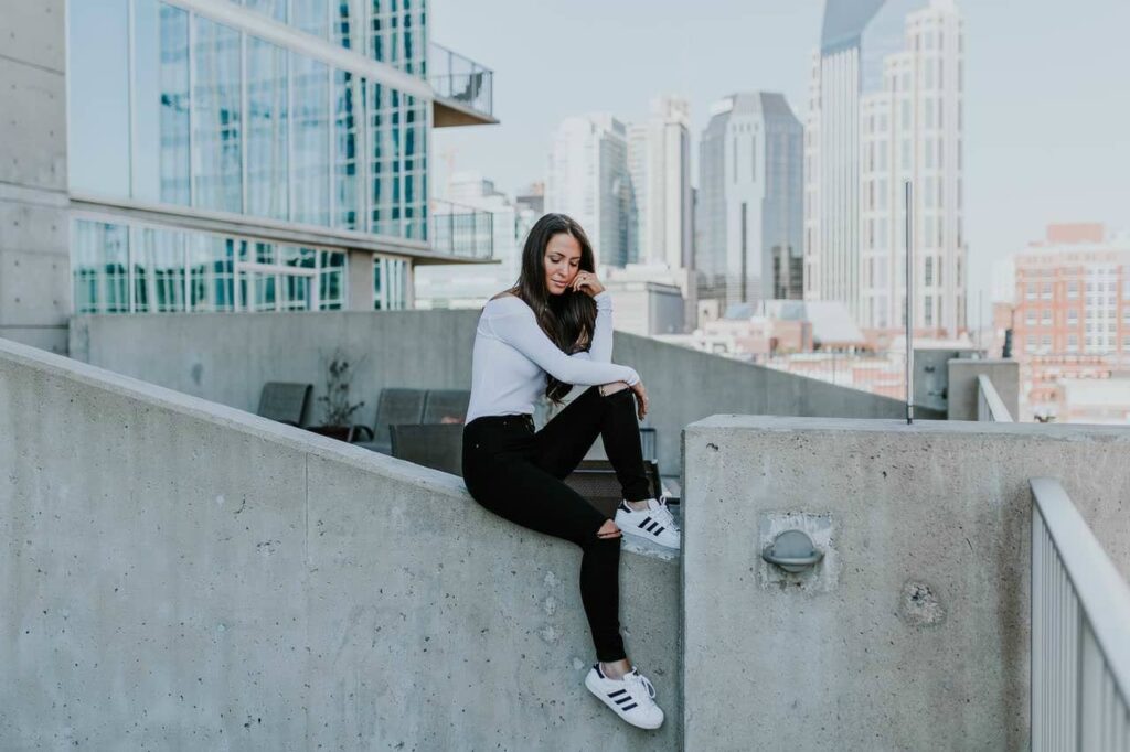 Woman seated on a rooftop ledge with a city skyline behind