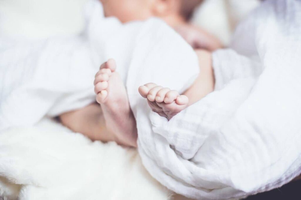 Newborn baby feet on white linen