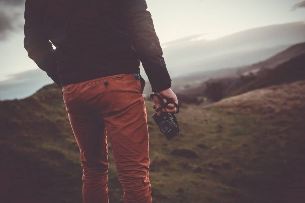 Photographer walking a coastal path holding a camera