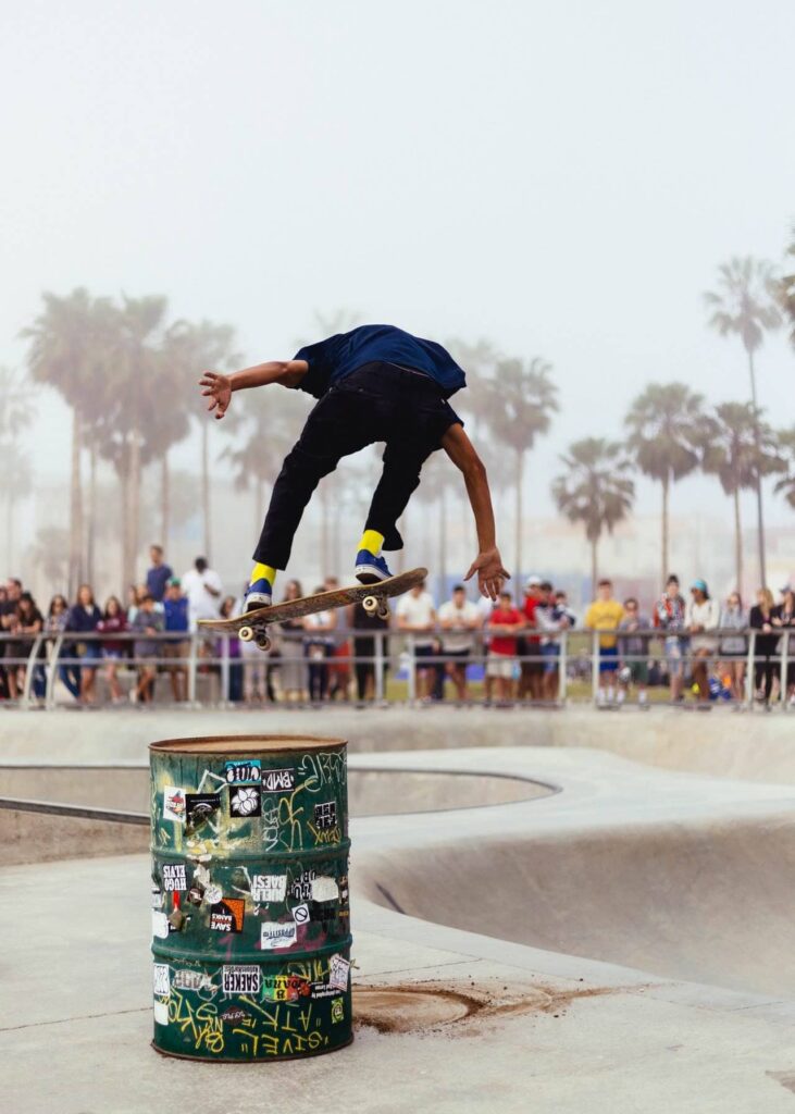 Skateboarder mid-trick over a bin at a skate park