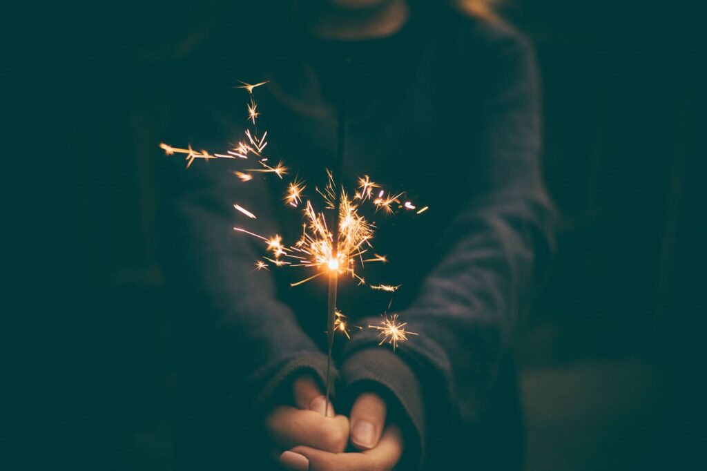Hand holding a lit sparkler in the dark