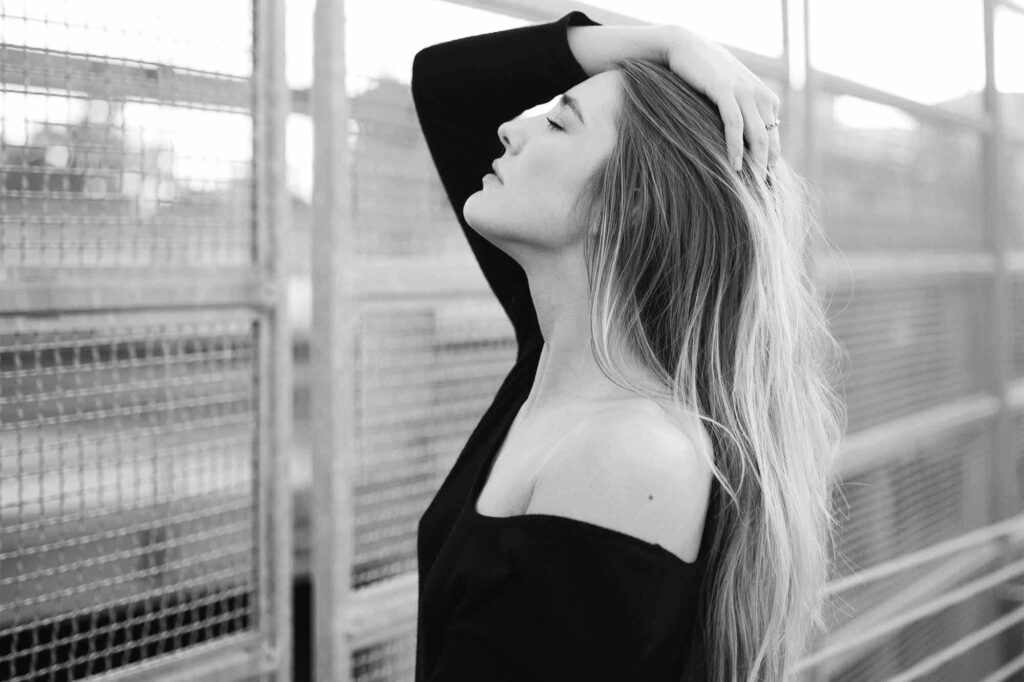 Black and white portrait of a woman with long hair on a rooftop walkway