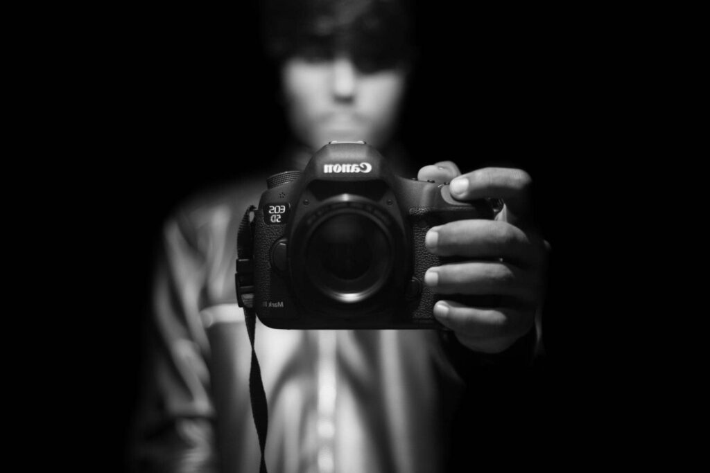 Photographer holding a Canon DSLR up to the camera in low light