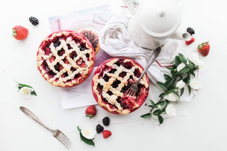 Overhead flat lay of two lattice berry pies with a teapot