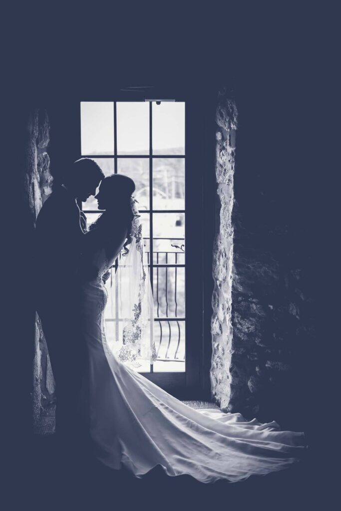 Bride by a tall window in a dark room