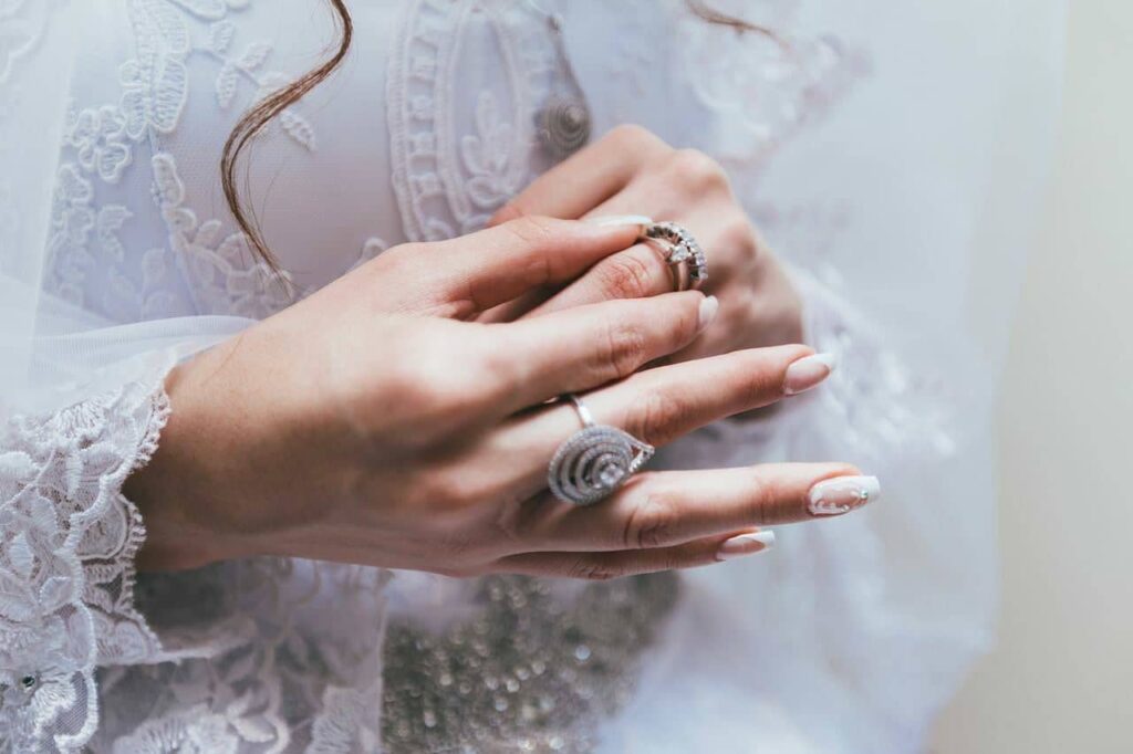 Hands wearing rings resting on a lace gown