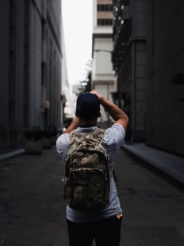 Photographer seen from behind with a backpack in a narrow city street