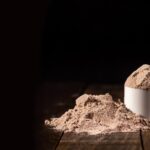 Scoop of whey protein powder on a wooden surface