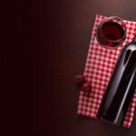 Red wine bottle and glass beside a bunch of grapes