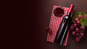 Red wine bottle and glass beside a bunch of grapes