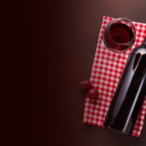Red wine bottle and glass beside a bunch of grapes