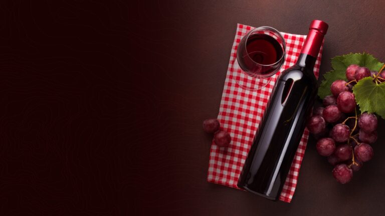 Red wine bottle and glass beside a bunch of grapes